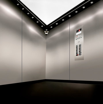 stainless steel inside of elevator lift with corner camera,  buttons and lights
