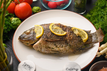 Eastern or European cuisine, Fried fish with fresh vegetables, on a wooden black background. I also eat healthy food. Seafood, recipe book, selling fish, restaurant business