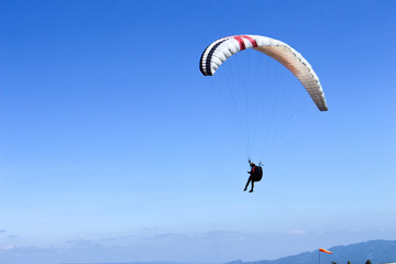 a paraglider flying in blue sky landscape in Indonesia