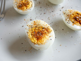 ฺBoiled egg topped with Cayenne pepper Pepper and Salt on a white dish,Egg colors white and yellow,Eat with bread