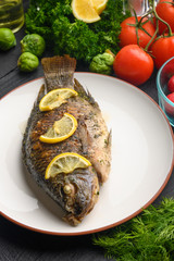 Cooked fish with ingredients, on black background. Vertical frame.
