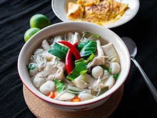 Food Thai name is Mushroom Tom Yum,Ingredients mushroom chilli lemon lemon grass Kaffir lime leaves Galangal and Coriander,saw blade,Black fabric background,Omelette, side dish