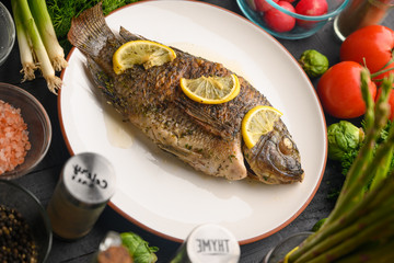 Stewed fish with lemons and fresh vegetables. Delicious and healthy food.