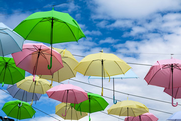 Fototapeta na wymiar colorful fancy umbrella line decorate outdoor moving by wind on blue sky white cloud