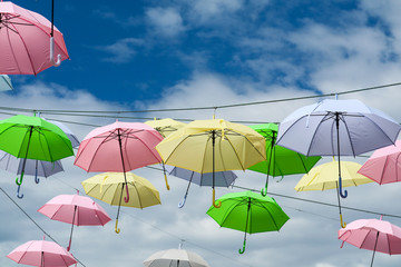 colorful umbrella line wire moving by wind on blue sky white cloud