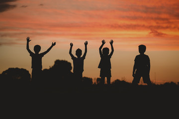 Children silhouette playing and jumping at sunset 