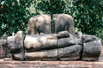 Fototapeta na wymiar Horizontal shot of Buddha statues resting on an old brick ruins in Ayutthaya, Thailand. Summer trip, tourism, adventures concept.