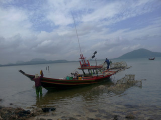 Naklejka na ściany i meble fisherman prepare their boat for fishing near the beach
