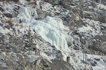 Fototapeta na wymiar Frozen water in the form of a huge glacier hang on the wall inside the quarry for limestone mining.