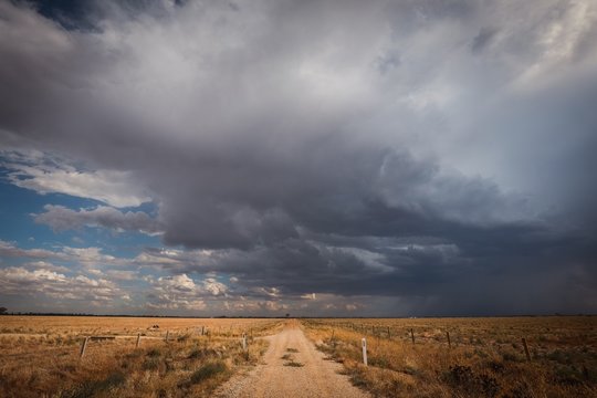 Storm on a country lane in remote central Victoria, Australia. Gravel road surrounded by dry paddocks in times of drought with the hopes of rain.