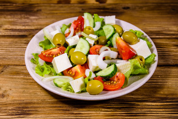Ceramic plate with greek salad on wooden table