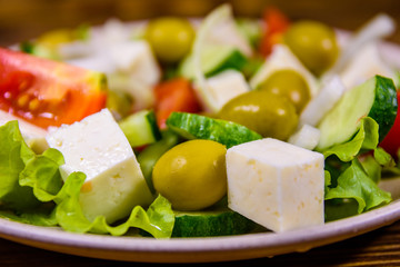 Ceramic plate with greek salad on wooden table