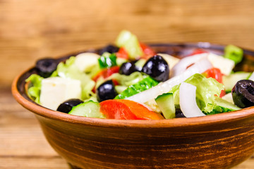 Ceramic plate with greek salad on wooden table