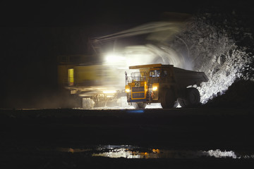 Blurry image of the excavator in motion on a long exposure loading stone ore into the body of a...