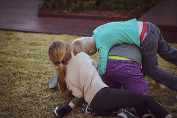Four children play wrestling on the lawn