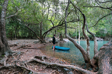 oung boy kayaking with paddle in cool blue water near waterfall at Cedar Creek Falls near Airlie Beach in the Whitsundays, Queensland Australia
