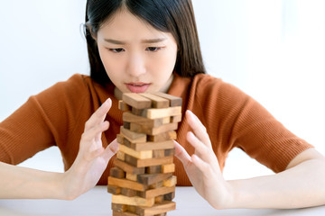 worry stress asian smart woman try to built and protect wooden stack tower risk management strategy...