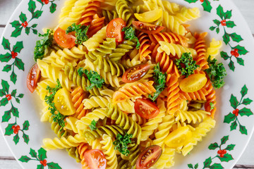 Colorful pasta rotini, cherry tomatoes on christmas plate. Close up.