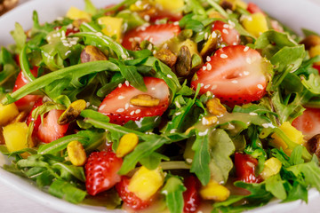 Green salad with arugula, strawberries, mango and pistachios.