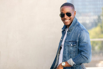 Fototapeta na wymiar Cool hip stylish african american man in sun glasses and a jean jacket, lifestyle portrait on rooftop