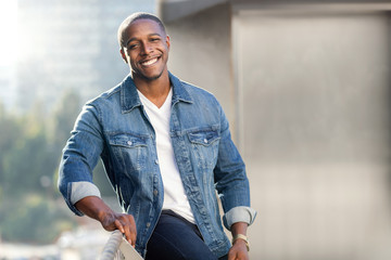 Portrait lifestyle head shot of an african american male in a blue jean jacket on a city urban...