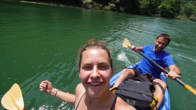 Couple on a kayak. Girl taking selfie while boy paddles