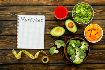 Diet program mockup. Start diet text in notebook near vegetables on dark wooden background top view
