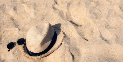 Fototapeta na wymiar Banner of hat and sunglasses on sand