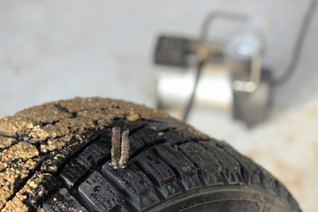 Tire repair thread compound on a car winter tyre close up on wheel pump background, self repair of punctured tire