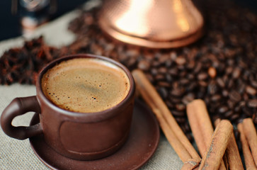 earthenware coffee Cup, coffee beans, cinnamon sticks, star anise, canvas napkin on dark background