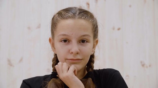Surprised thoughtful girl thinking and looking up. Close-up portrait of beautiful pensive teenage girl with hand on chin