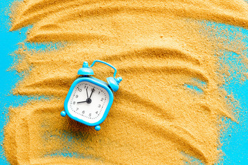 Deadline concept. Clock on sand on blue background top-down