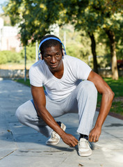 Athletic african  american male in  headphones before running  in park