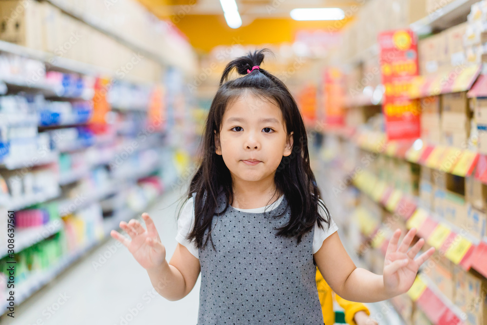 Wall mural Surprised and excited face of happy little asian girl in supermarket with mom.Little girl open mouth in hypermarket with family.wow emotion in kid.