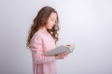 a little girl with a book  smiling isolated on a white background