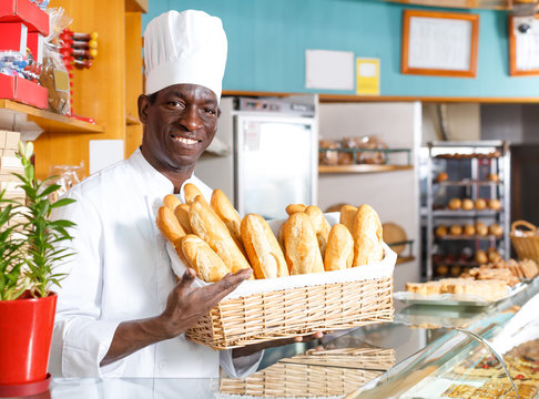 Adult African American baker holding baguettes