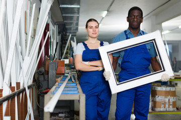 Portrait of man and woman worker who are standing with window frames