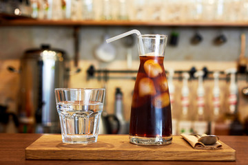 Glass with cold brew coffee and glass with water on a coffee shop counter