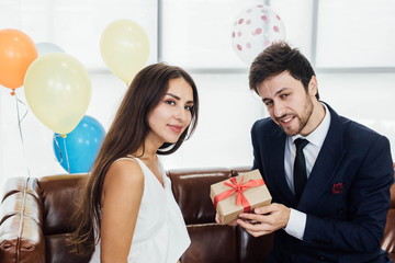 Young couple celebrating new year together, boyfriend gives a present to girlfriend.