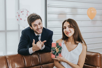 Young couple celebrating new year together, boyfriend gives a present to girlfriend.