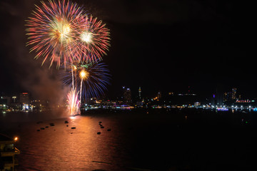 Pattaya International Fireworks Festival. Fireworks over cityscape by the beach and sea surrounding with Pattaya city alphabet in the night scene. 