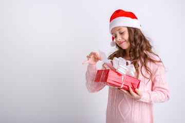 smiling little girl in Santa hat with gift in hand on isolated white background