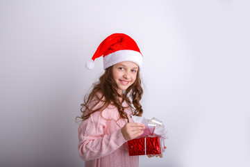 smiling little girl in Santa hat with gift in hand on isolated white background