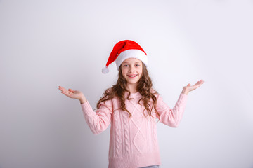 smiling little girl in Santa hat on isolated white background spread her arms to the sides shows surprise