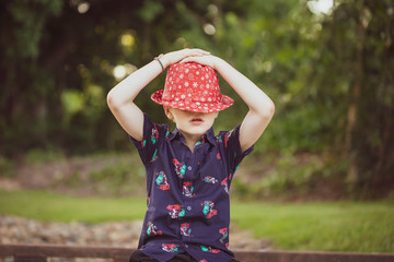 Child wearing vibrant Christmas shirt and eye catching holidays hat being silly with eyes covered