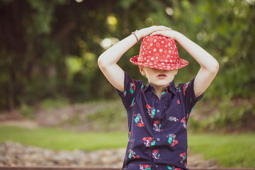 Child wearing vibrant Christmas shirt and eye catching holidays hat with eyes covered