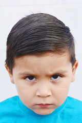 Unhappy little latin boy. White background.