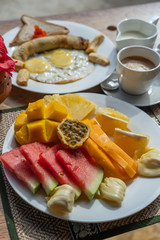 Tropical breakfast of fruit, coffee and scrambled eggs and banana pancake for two on the beach near sea