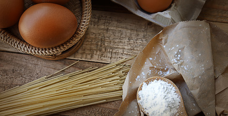 Bread and flour - Top view, ingredients to make baking on a wooden table, a bowl flour, eggs and macaroni