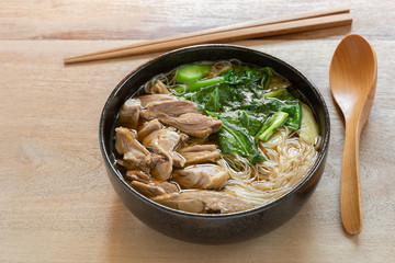 rice vermicelli soup with sliced duck meat in a ceramic bowl on wooden table, close up. delicious food menu.